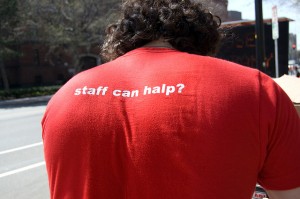 Man wearing a shirt that reads "staff can halp?" on the back.